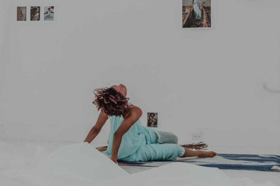 A black woman lays on the ground in an art exhibit.