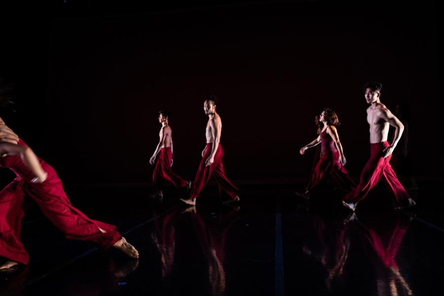 On stage, four dancers, in red outfits, walk behind an impassioned performance.