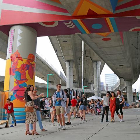 Outside, in an underpass, folks pose with brightly colored murals.