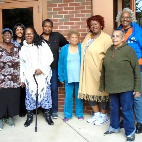 A group of women of color pose in front of a brick building.