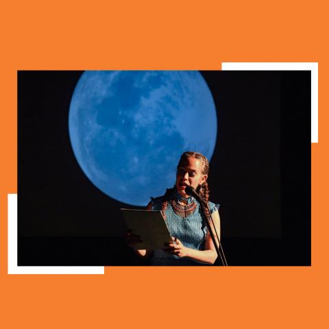 In front of a large projection of the blue full moon, Yara reads into a microphone.