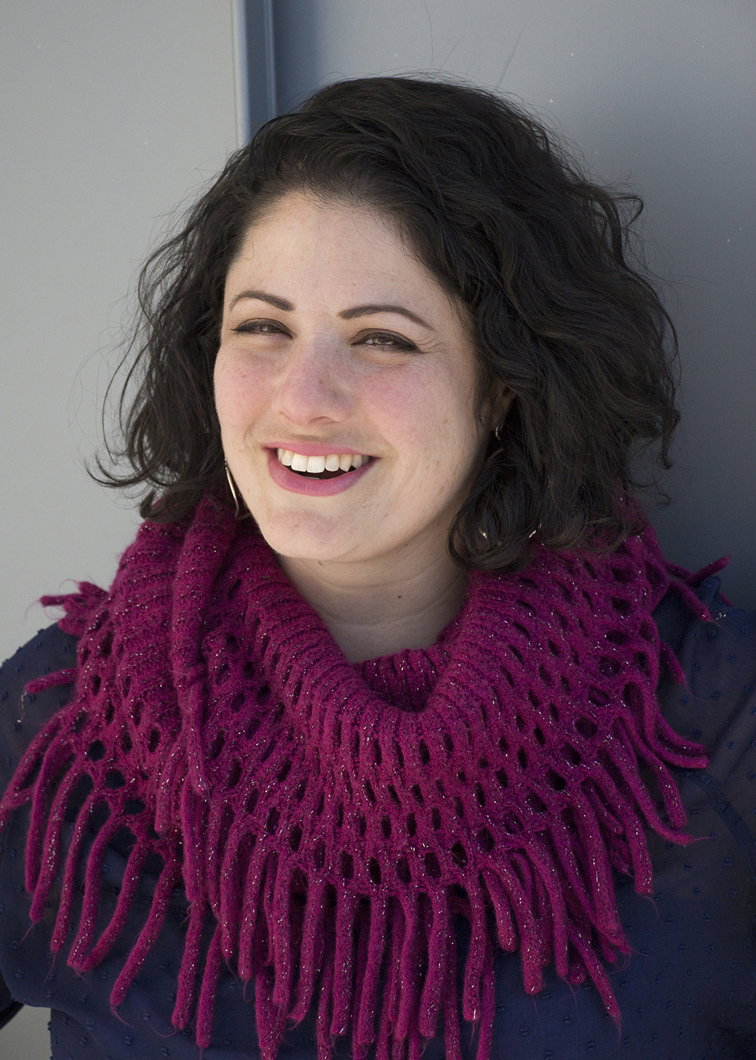 Denise smiles away from the camera, while wearing a pink knitted scarf