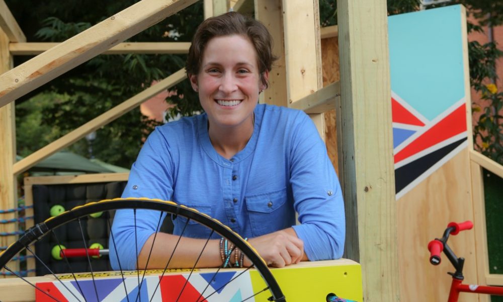 Amy leans over a wooded structure with shapes painted on it