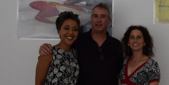 Lisa, Brad, and Suamy pose in front of a classroom wall, with educational posters behind them.