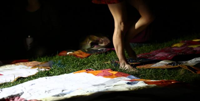 A woman walks over fabric laid over grass.