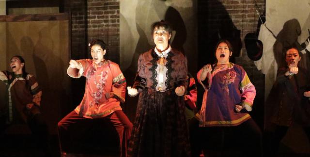 Five Chinese women in traditional colorful clothing standing next to each other with fighting poses and fierce facial expressions