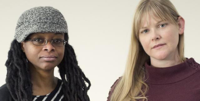 Molly and Zahra stare at the camera in front of a grey backdrop.