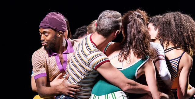A group of people in bright colors and prints huddle.