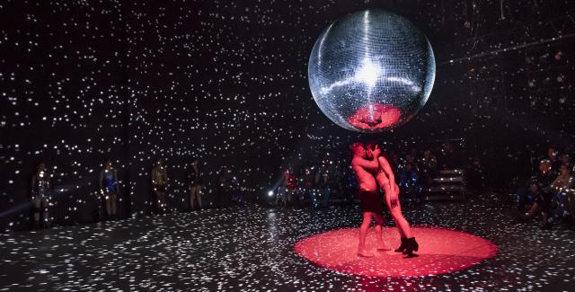 Two figures make out under a large disco ball.