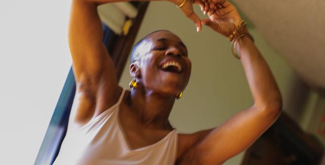 A performer holds their hands above their head in a heart shape.