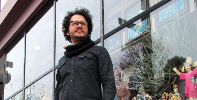 Salavador poses in front of a store front with Christian figurines.