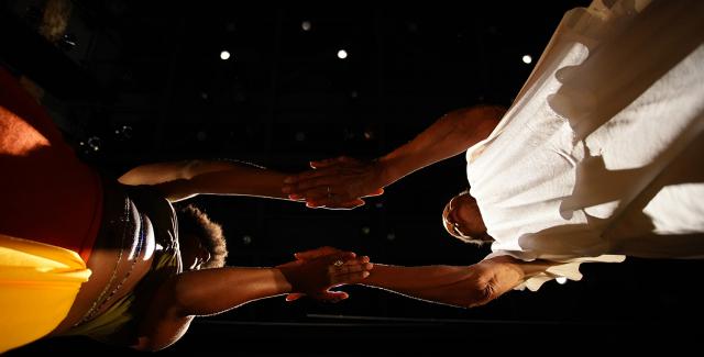 From below, two Black women lay their hands on flat on top of each others.