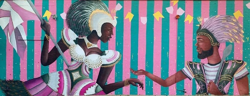A mural of two Black folks with feathered headresses and beaded armor.