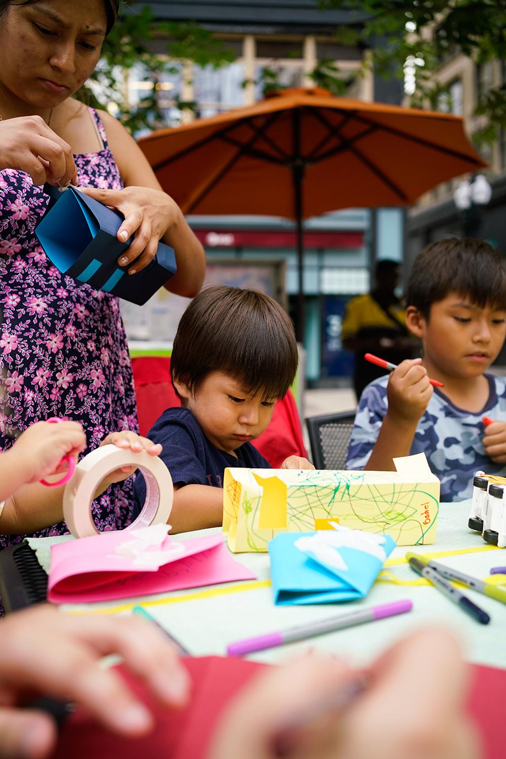 Young Asian boys sit at a table and make crafts.