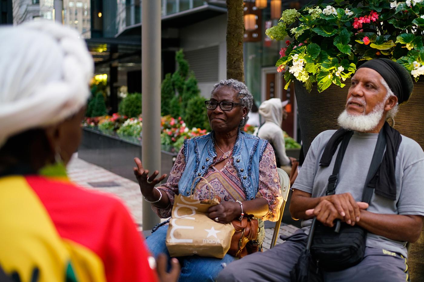 Four Black elders sit together and chat with their hands.