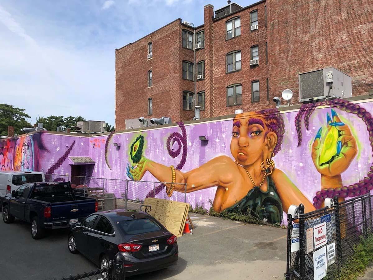 A mural of a woman with braids, who holds avocados like jewels.