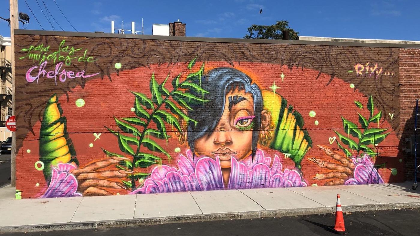 A mural of a woman of color with green and purple leaves.
