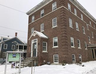 A large, old brick house covered in snow. A sign in front reads: The Center for Arts and Learning