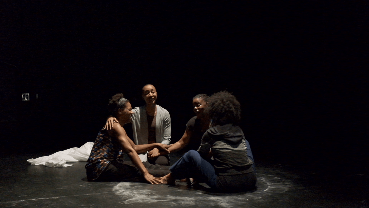 On a stage, four women sit in a circle facing each other.