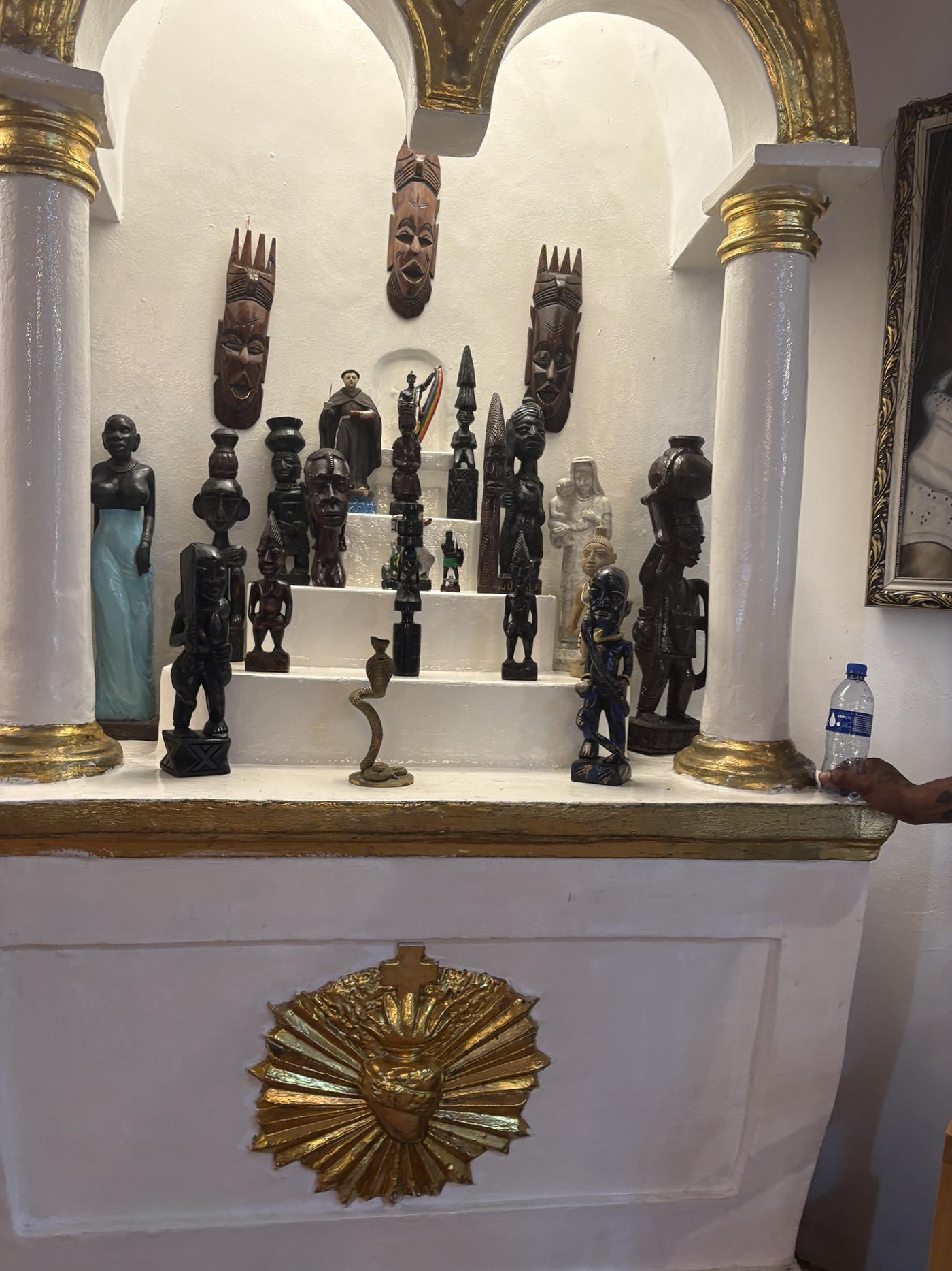 A white and gold altar, with small dark brown statues.