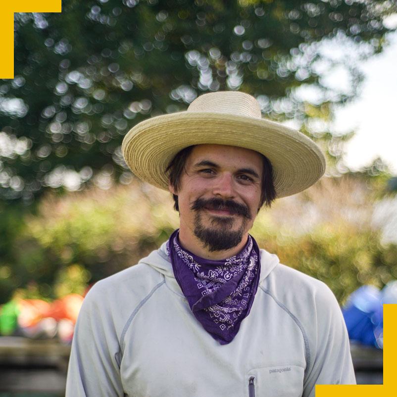 Chris poses in a straw hat and purple handkerchief.