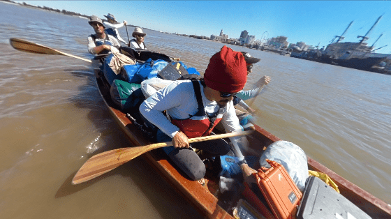 Chris wears a beanie and paddles a canoe with two other folks.