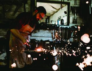 a blacksmith at the welding station - sparks fly amongst heavy machinery