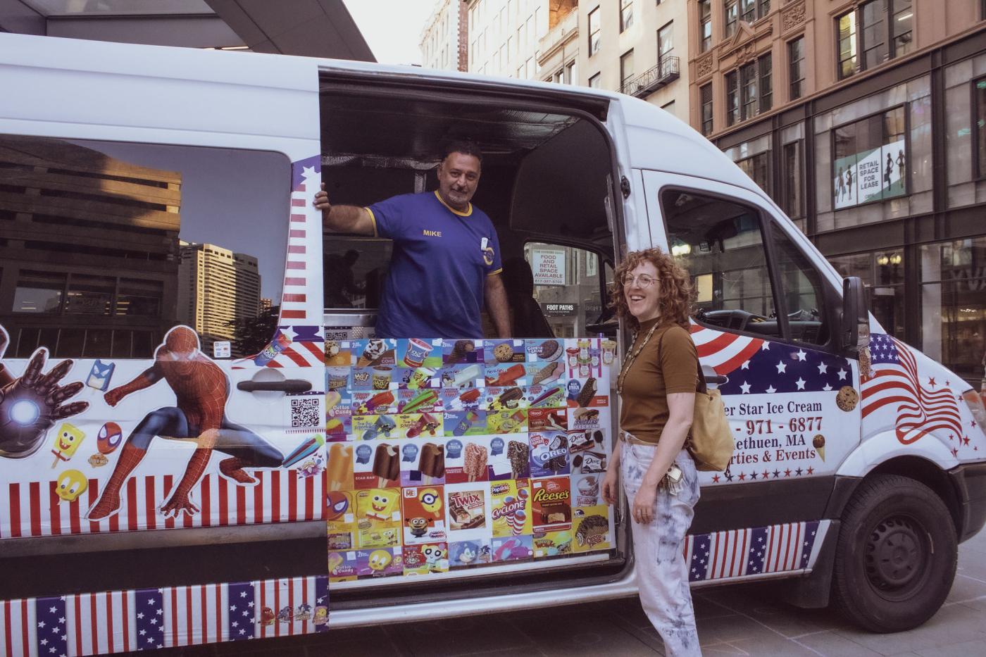 A white woman poses with a man inside an Ice Cream Truck.