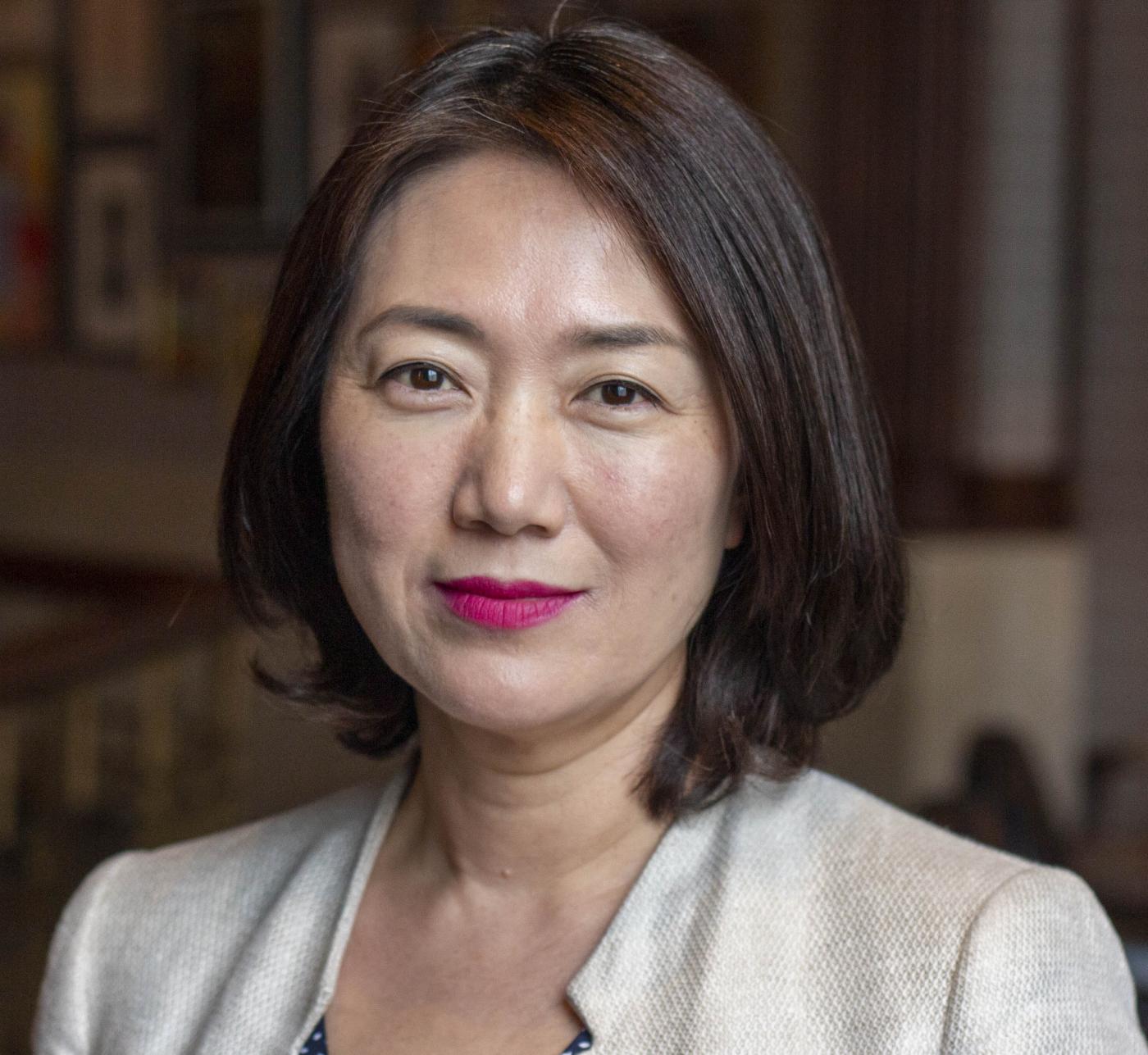 Head shot image of board member Min Jung Kim; she is smiling and wearing a ivory jacket.