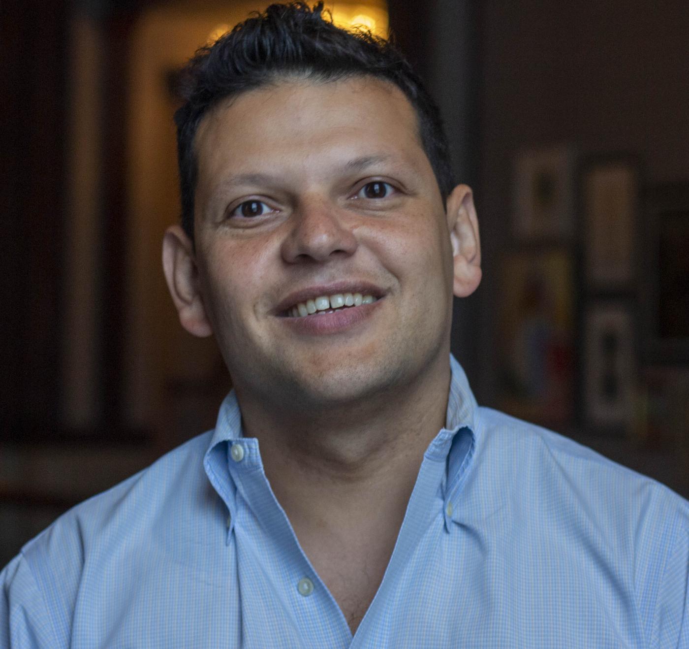 Head shot image of board member Ivan Espinoza-Madrigal; he is wearing a blue shirt and smiling.
