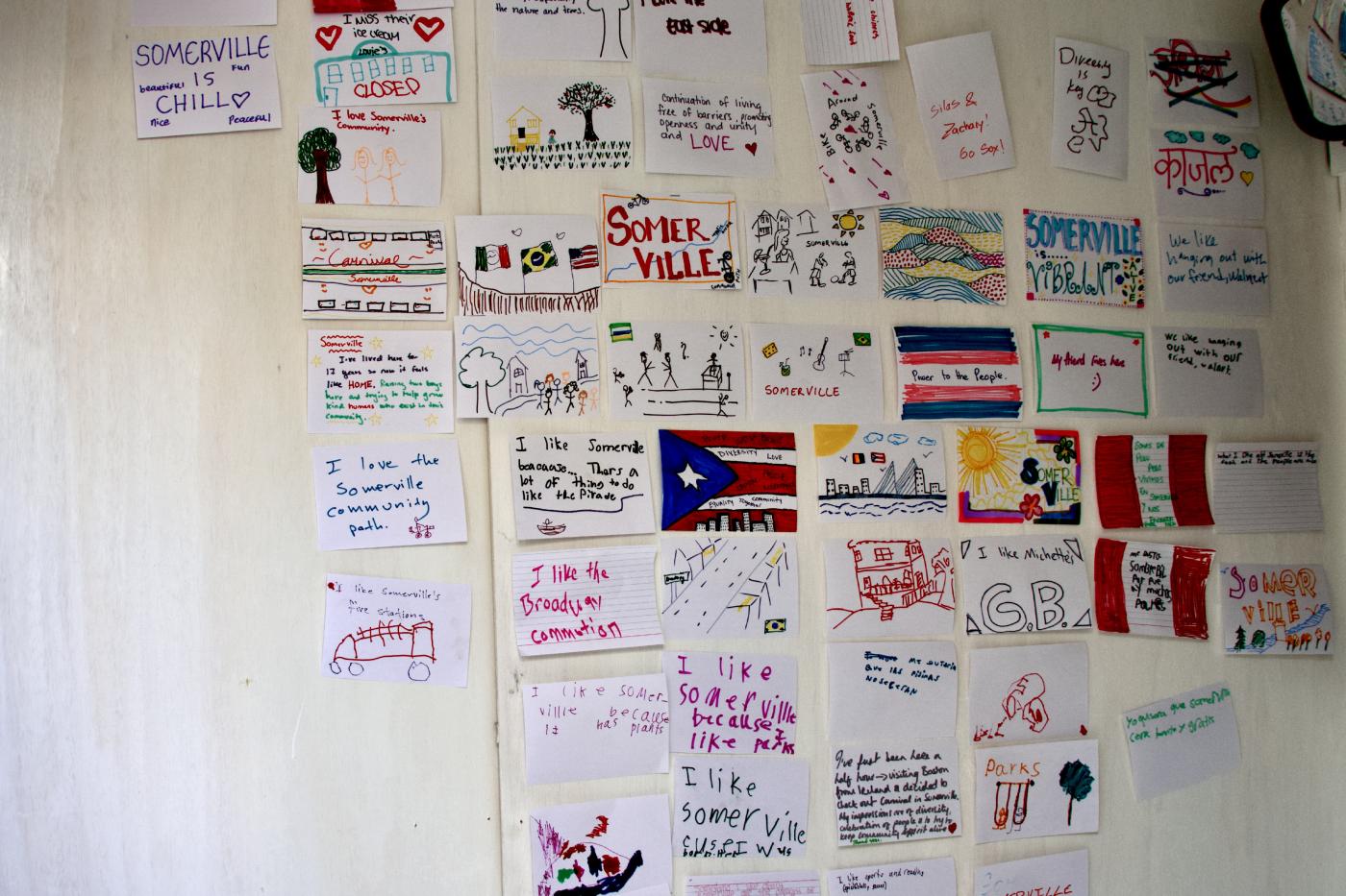 A wall with a collection of hand drawn illustrations on 8.5x11 paper sheets.
