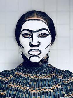 Lily has her face painted black and white. Black lines highlight the bones of Lily's face.