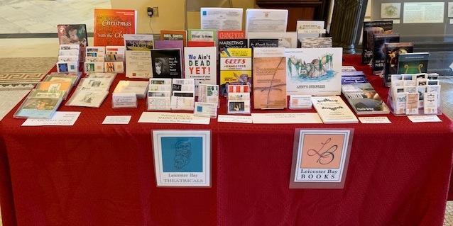 a display of various books and plays on a table at a convention