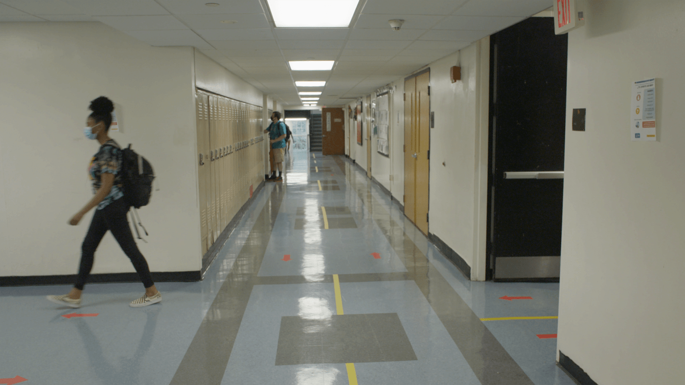 In a school hallway, a student walks.