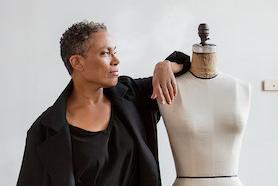 A woman leans on a mannequin.