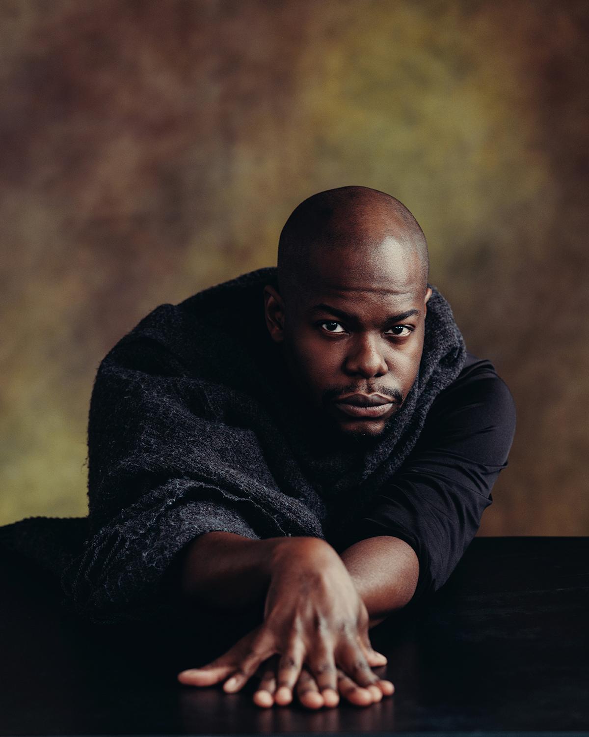 Jaamil poses with his hands on top of each other in front of him.