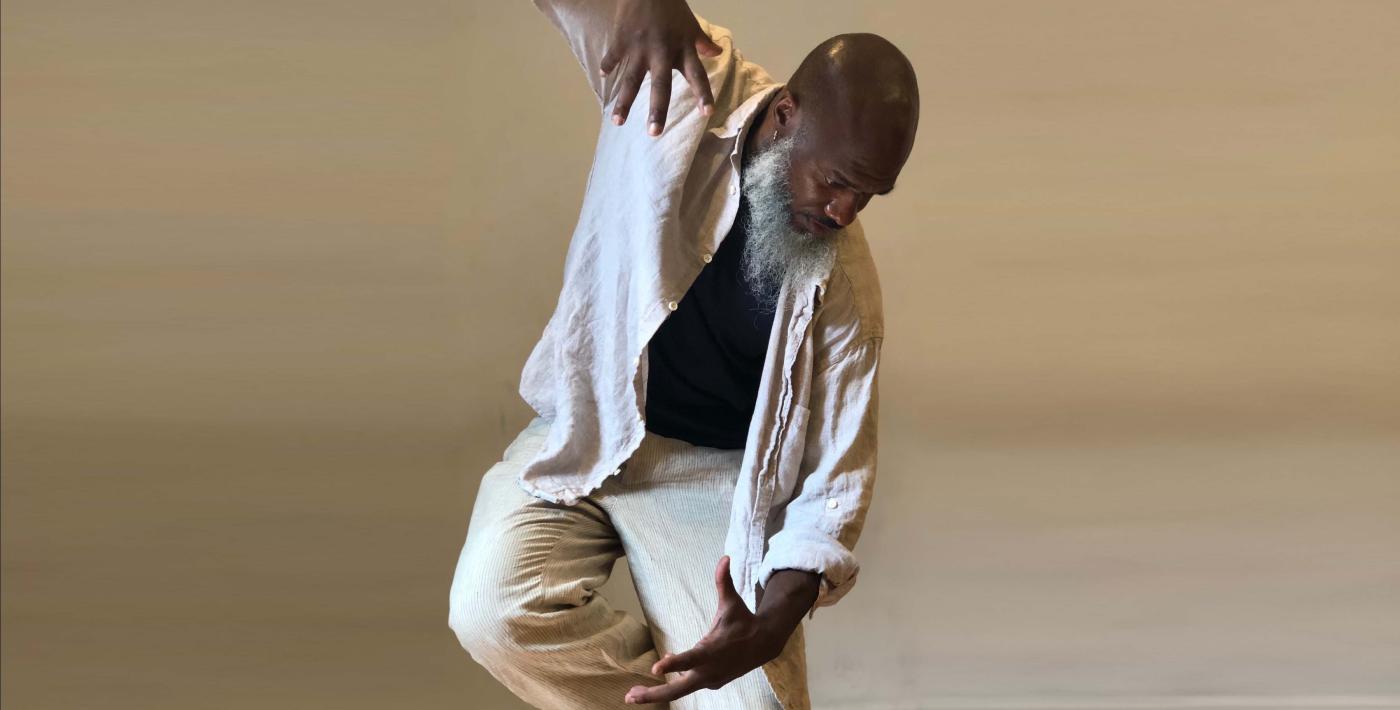 In a photo studio and wearing a white cotton top and bottom, Xavier holds his palms up and down as if they're tethered together by an invisible force.