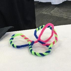 A swirly pipe cleaner sculpture with a bright yellow cleaner braided into it.