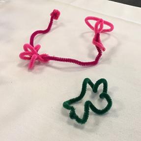 A pink and a green pipe cleaner sculptures. These are floral-inspired.