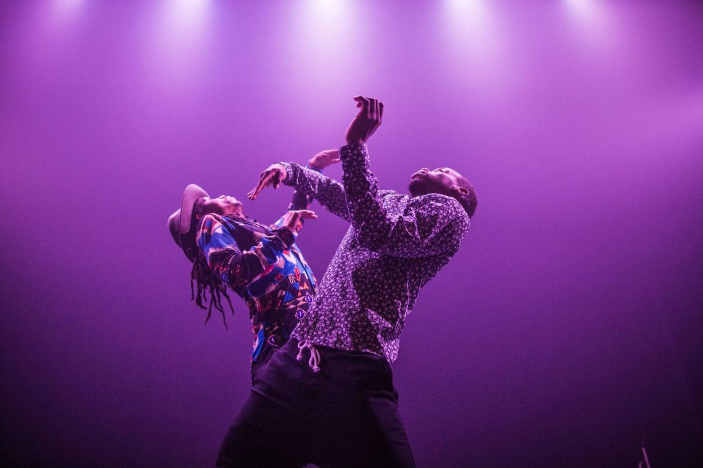 Jon Boogz and Lil Buck throw their arms up on a stage with purple lights