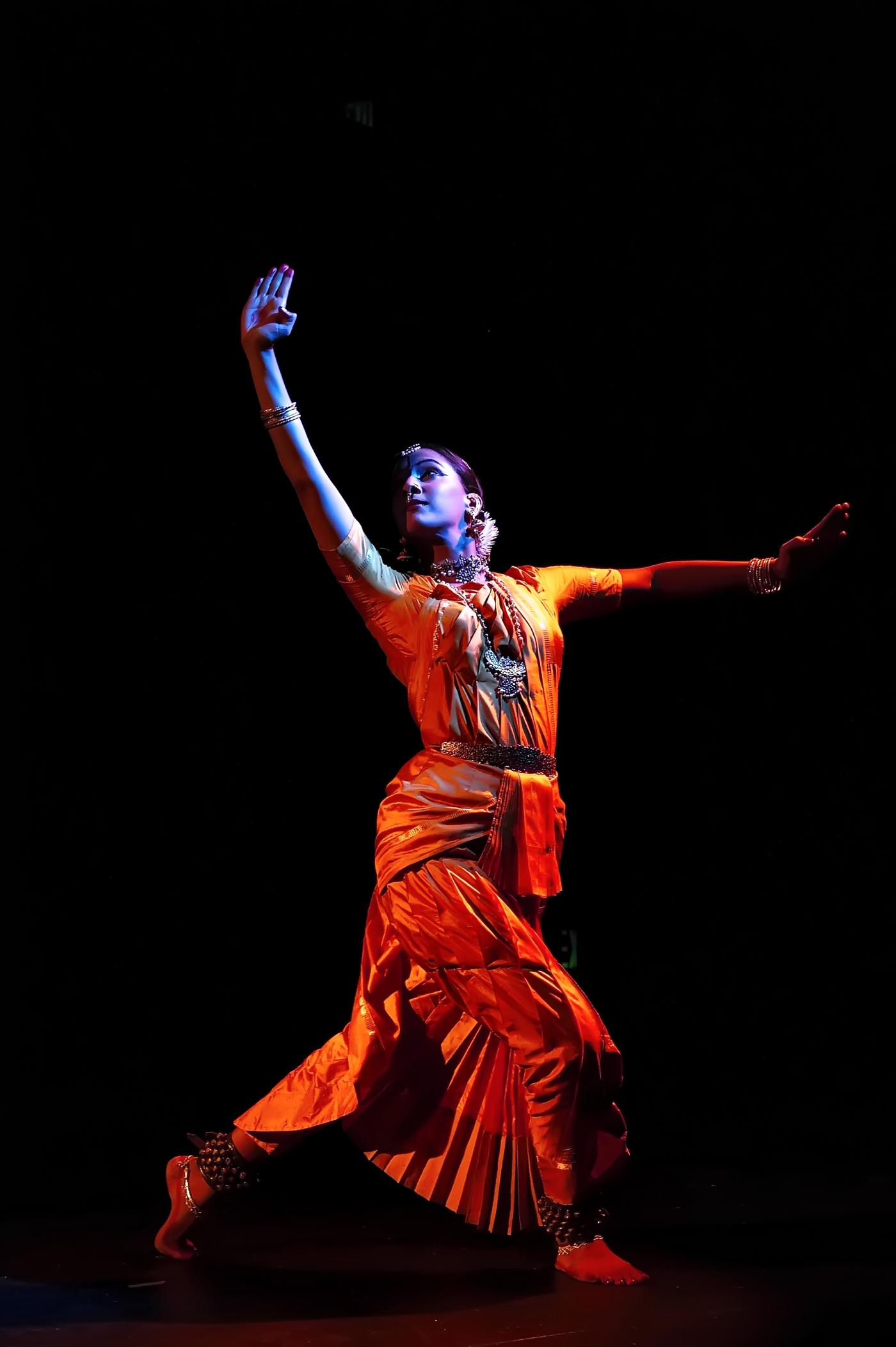 In a spotlight, Mythili dances in traditional Indian garb.