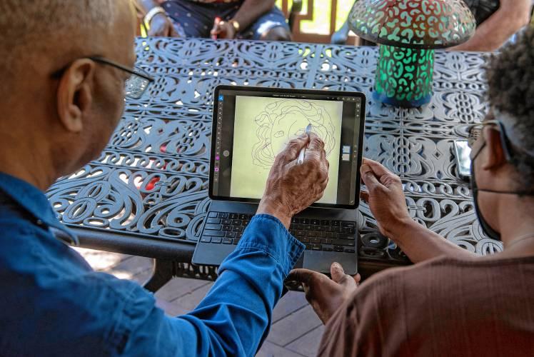 On a patio, two elderly folks sketch together on an iPad.