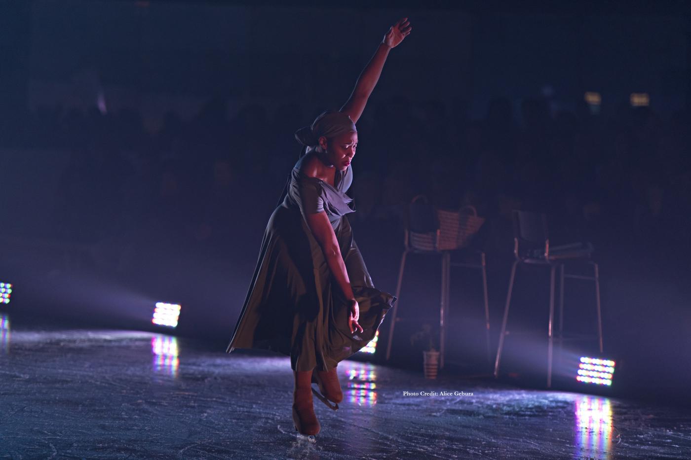 A Black ice skater holds her arms up and down.