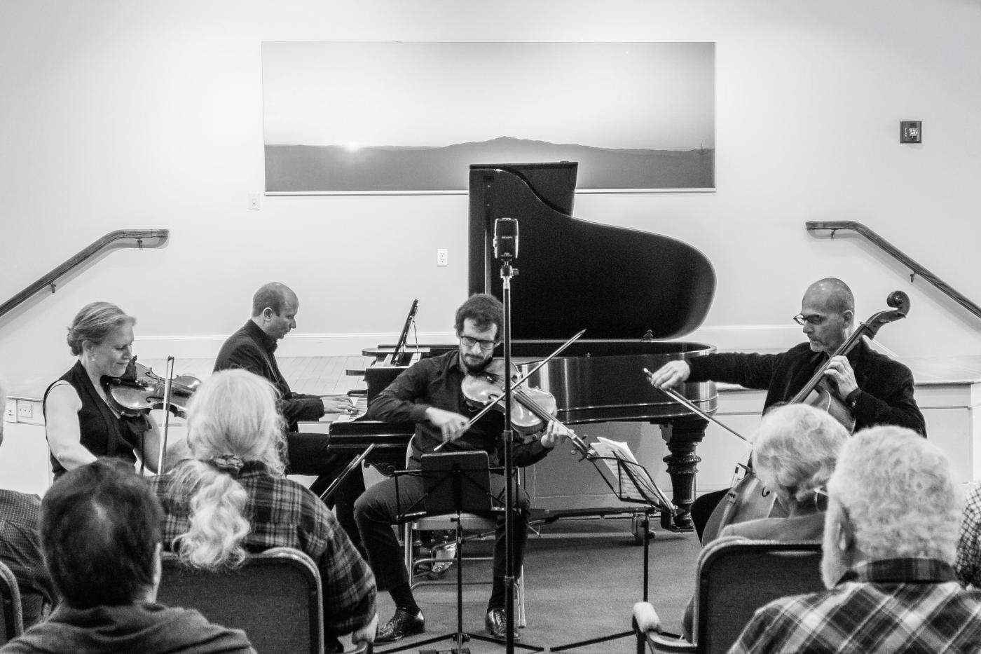 a quartet of musicians play piano, cello and violins in front of an audience