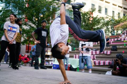 A young, Asian man leaps onto his hand.
