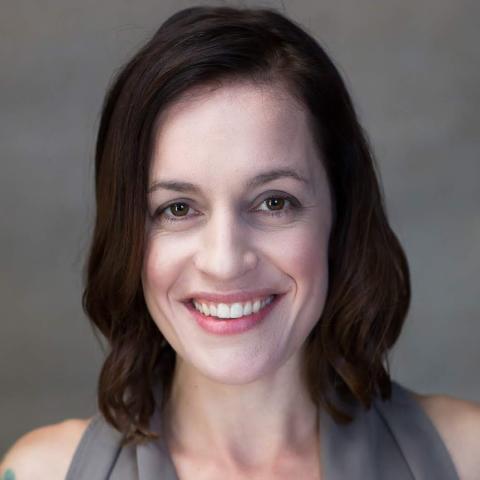 In a studio with a gray backdrop, Amanda smiles.