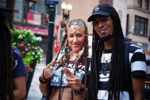 Two folks with long dreads smile and pose together.