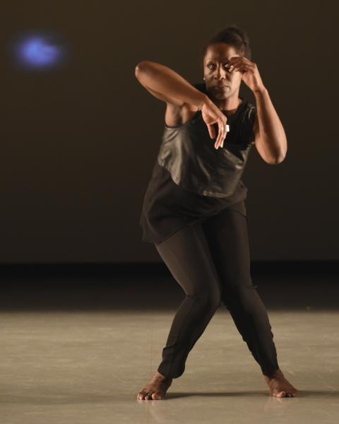 Deborah Goffe holds her hands up and bends her right leg. She is a Black woman with her hair pulled back.