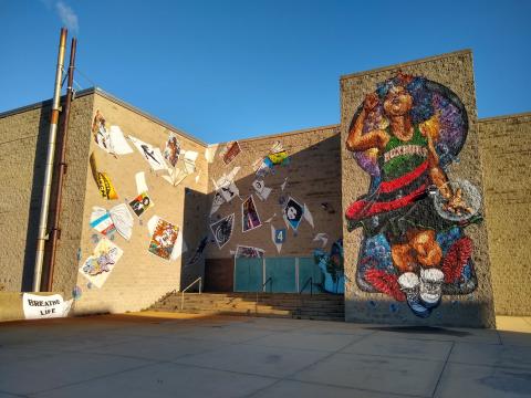 A mural of a young Black boy, in a basketball uniform, blowing bubbles next to a collection of smaller images.