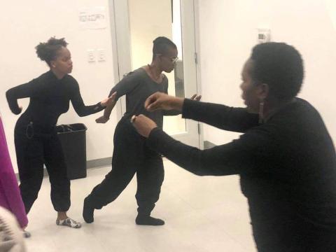 In a studio space, three performers in black leotards.